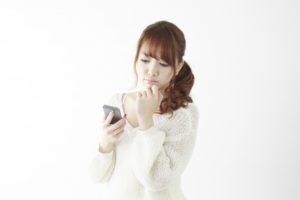 スマホを見ながら困っている女性